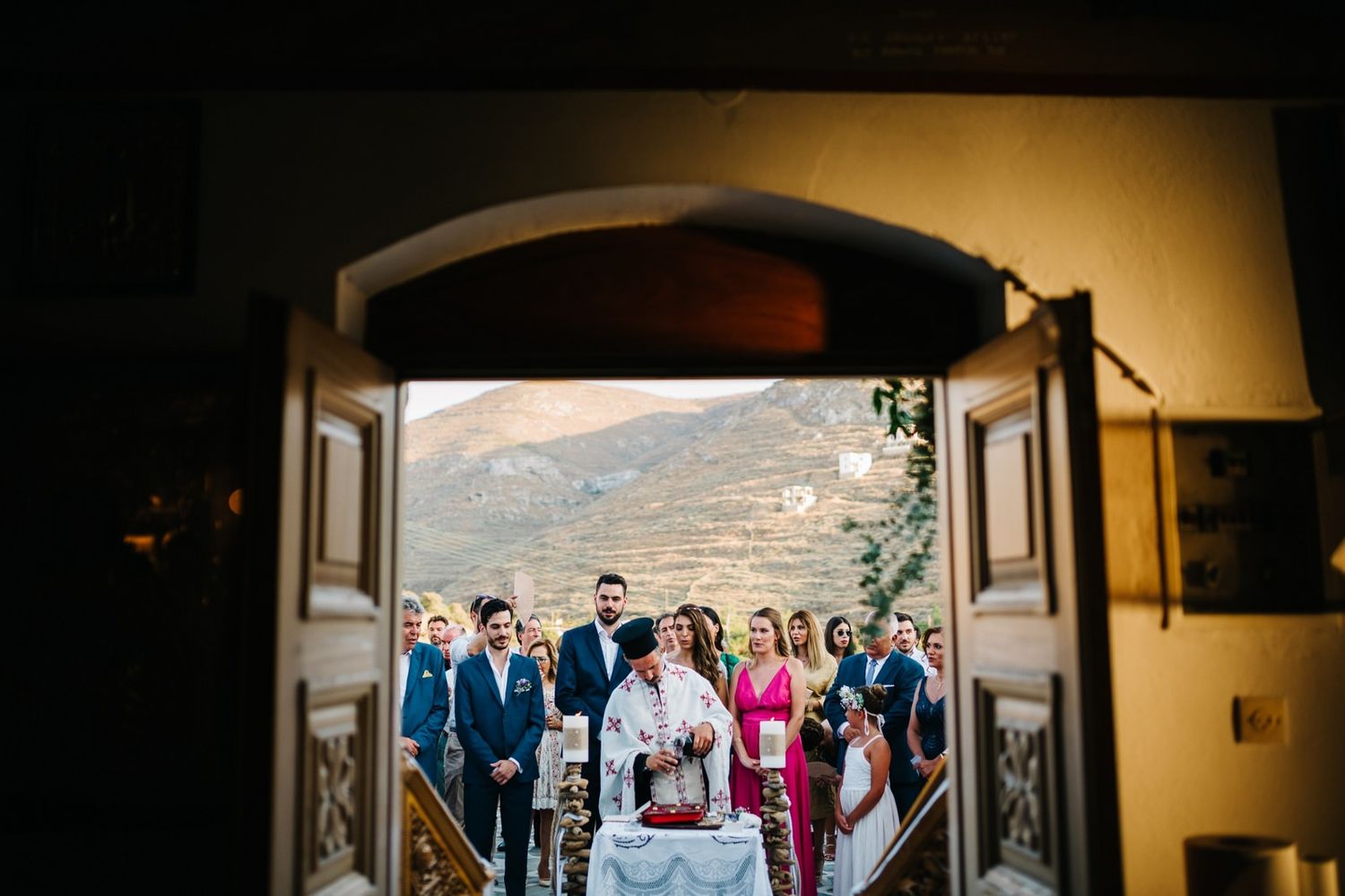Wedding party entering through arched doorway with mountain vista in background.
