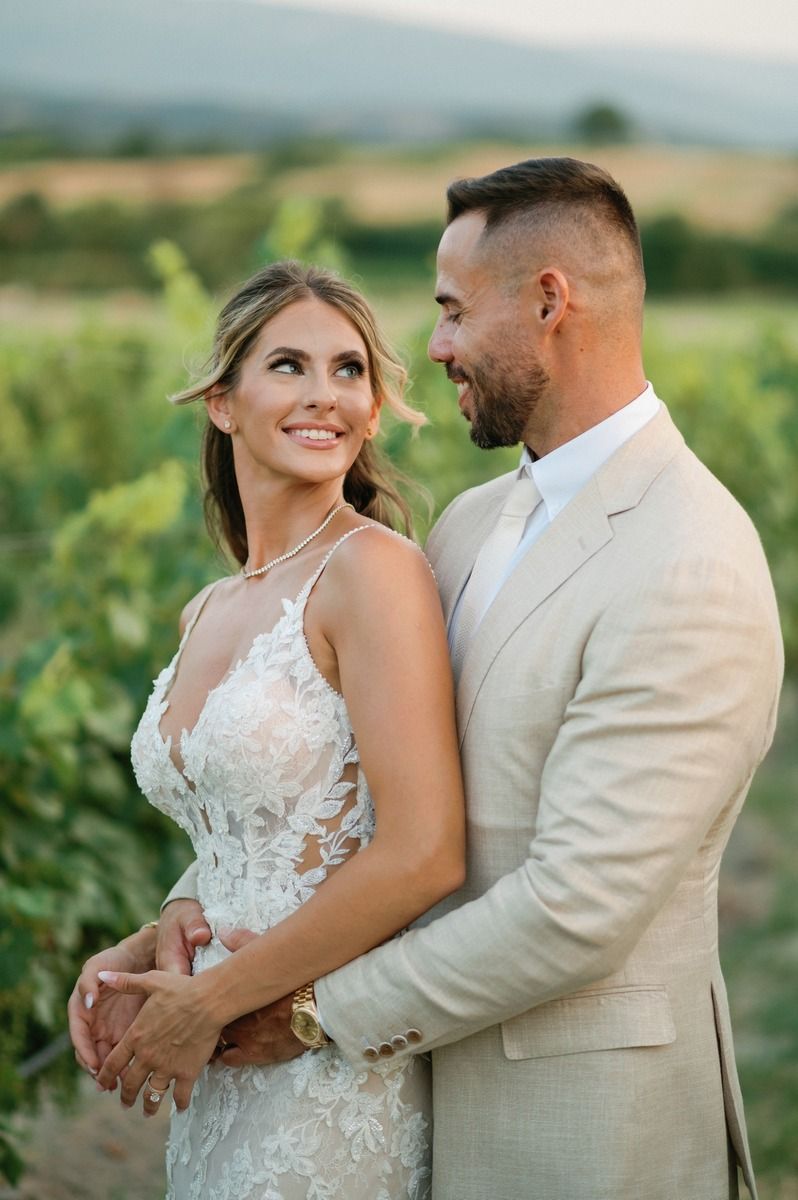 A couple shares an intimate moment among vineyard rows during their wedding photoshoot.