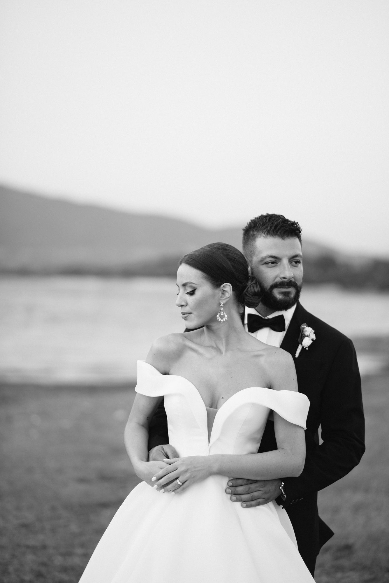 Black and white wedding photo series showing romantic moments between newlyweds against a scenic outdoor backdrop.