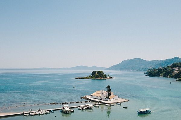 Scenic coastal landscape with boats docked at a pier overlooking mountains and blue waters in the Mediterranean.