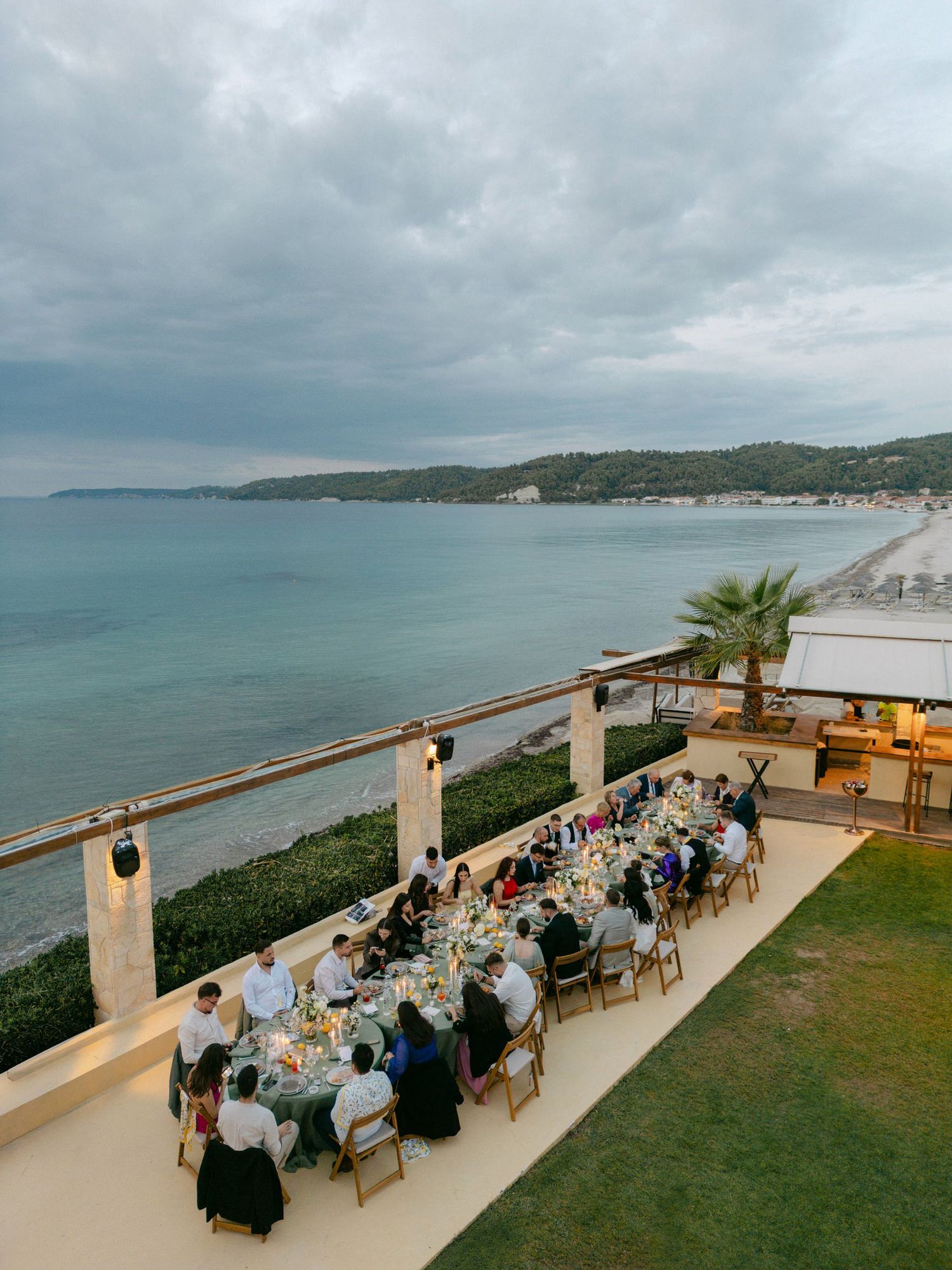 Panoramic sequence of an oceanfront wedding reception setup on a terrace overlooking a scenic coastal landscape at sunset.