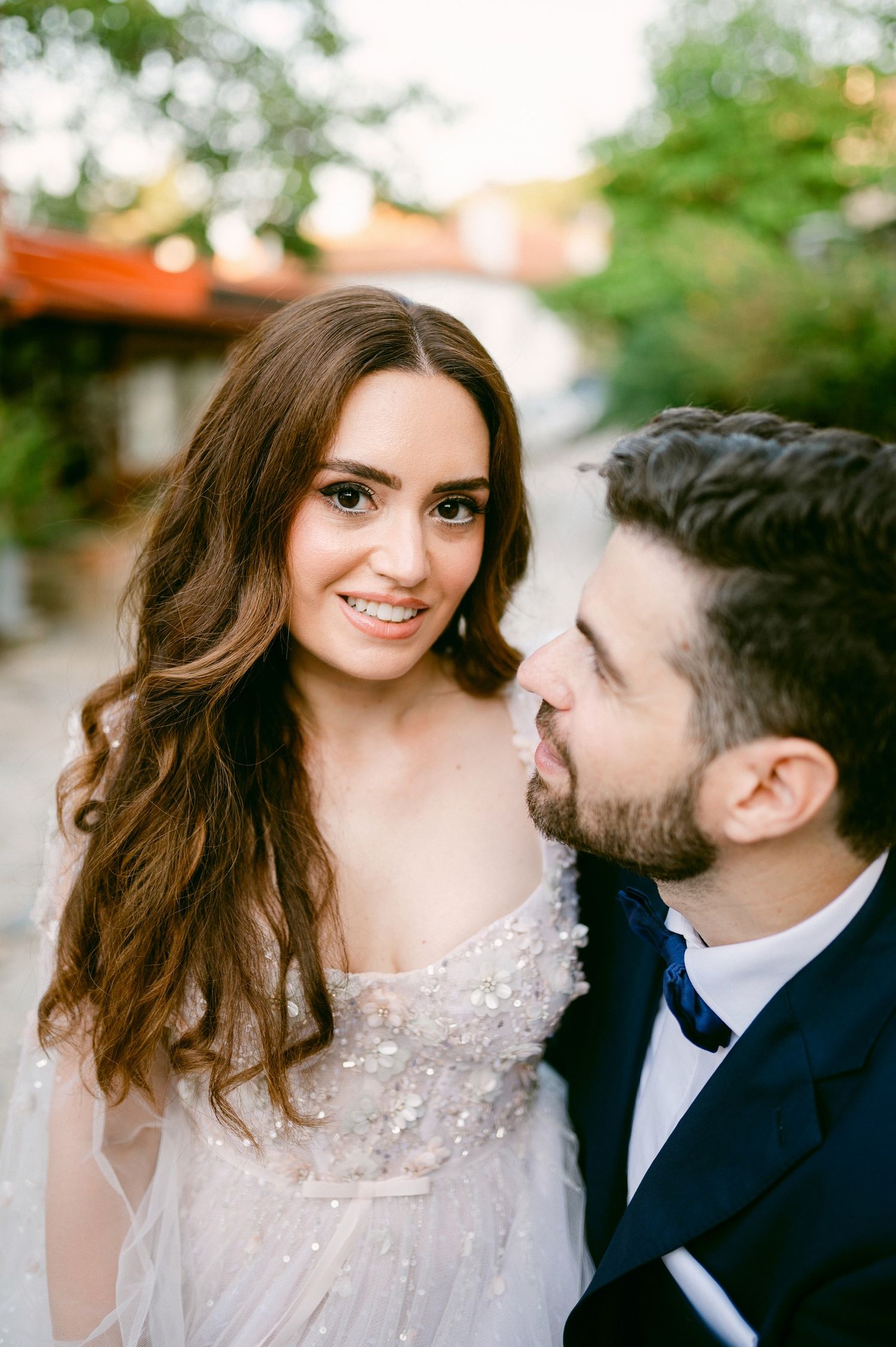 Elegantly dressed couple in wedding attire share an intimate moment outdoors during their special day.