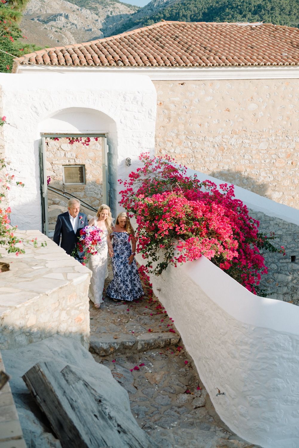 Stone archway adorned with pink bougainvillea flowers at Mediterranean wedding venue.