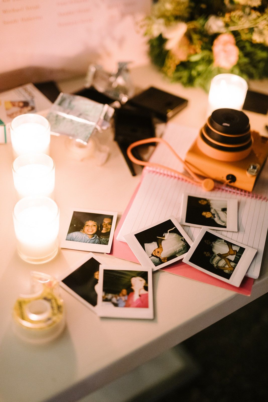Vintage camera and polaroid photos displayed on table with candlelight at wedding reception.