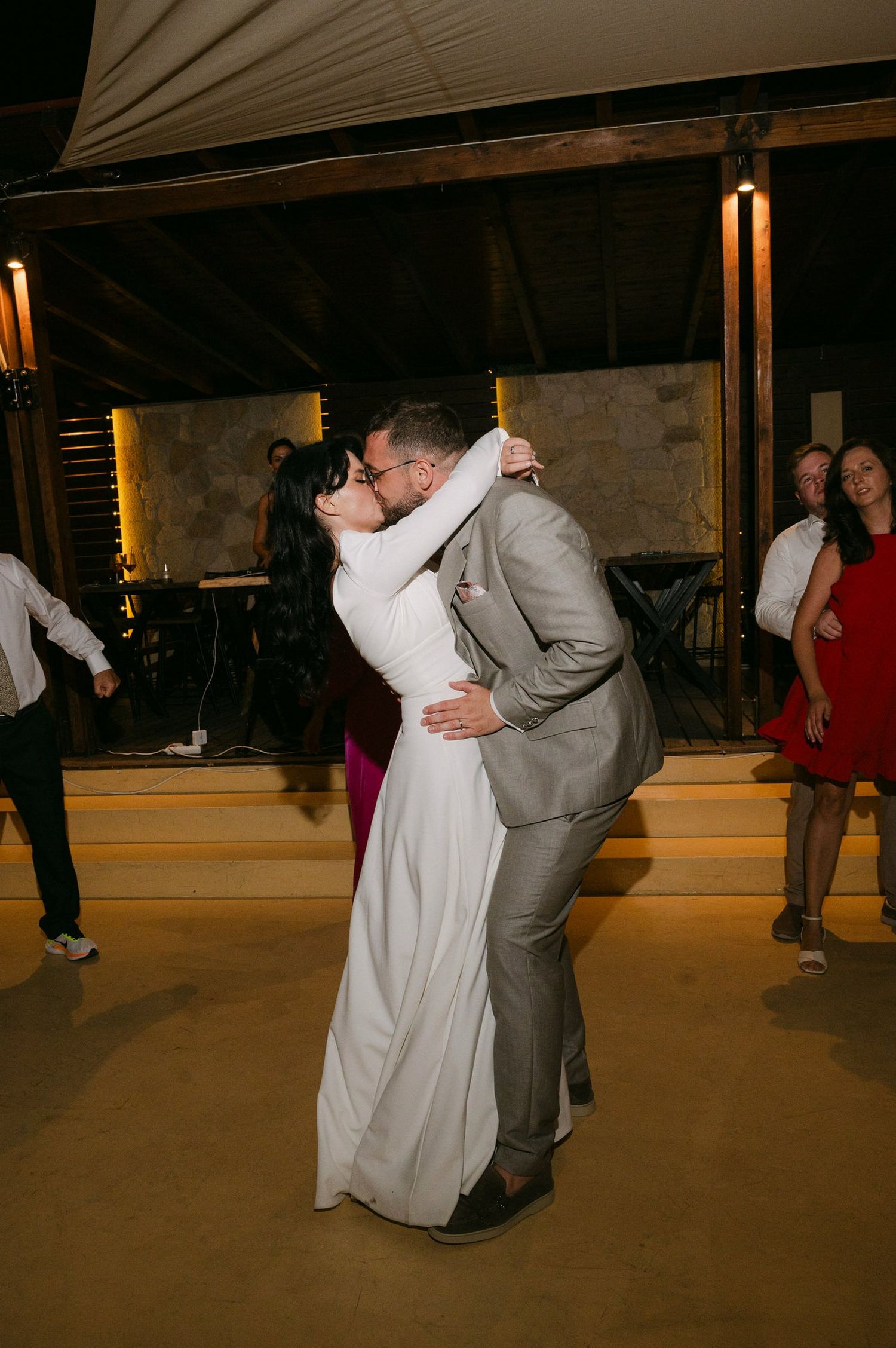 A couple performs a dip dance move during a wedding reception on a dimly lit dance floor.