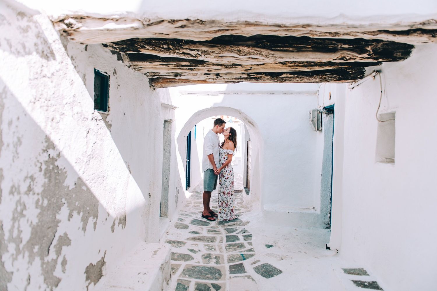 Couple stands in rustic white arched passageway with stone floor.