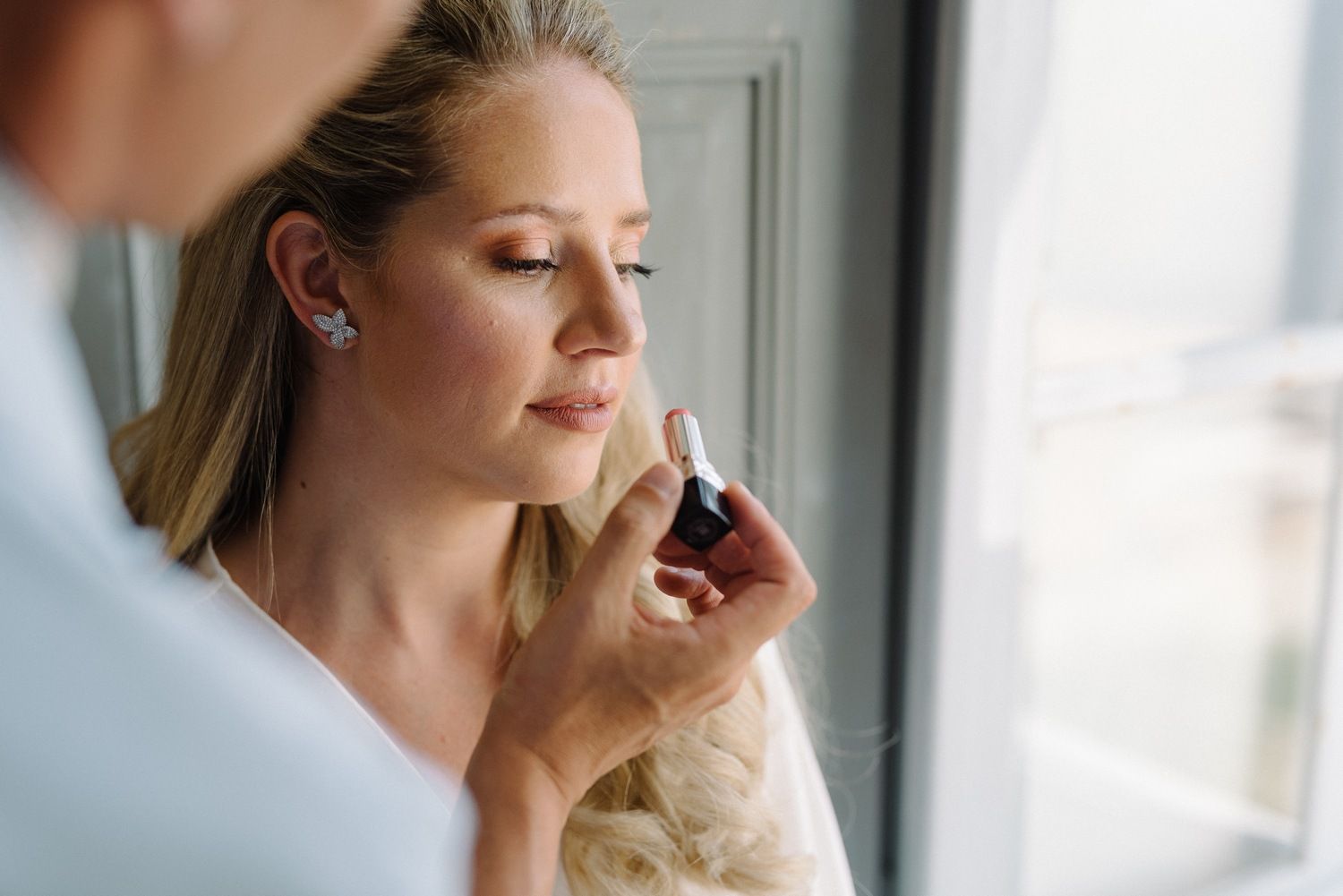 Woman in white blouse sitting peacefully by a window with ocean view.