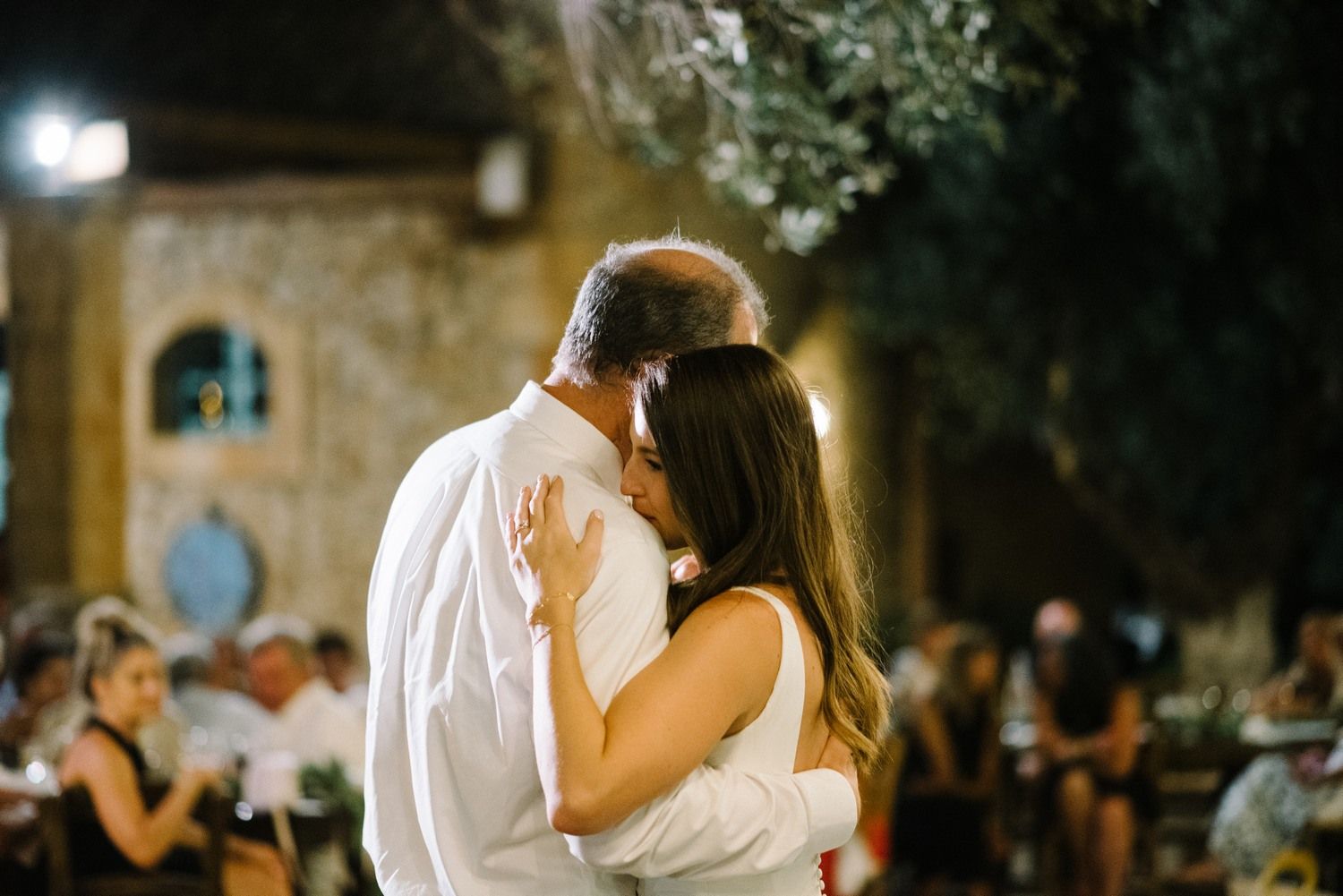 Intimate dance moment between couple at outdoor evening wedding reception.