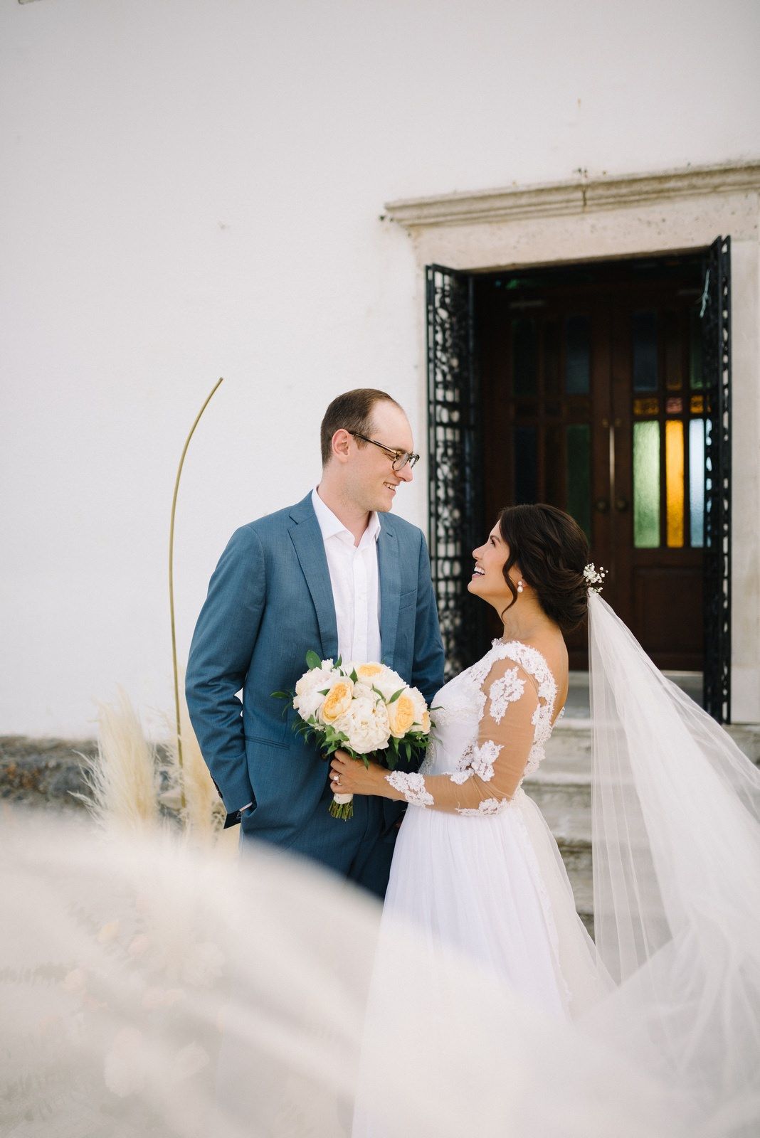 Romantic wedding portrait with bride and groom outside white Mediterranean building.