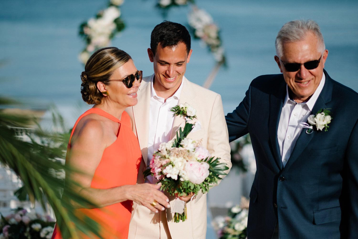 Wedding guests gathered on a sunny beach terrace with ocean views and tropical decor.