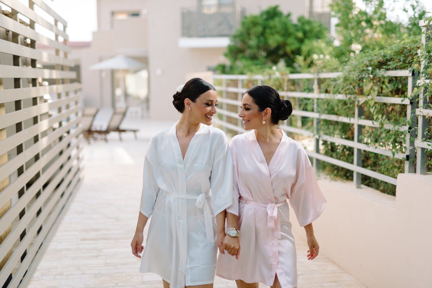 Two people in matching robes walk together on an outdoor terrace.