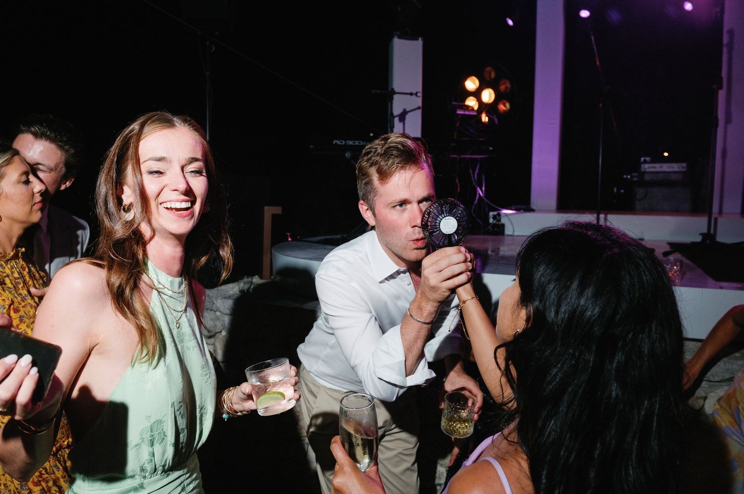 Candid party scene with guests dancing and photographer capturing moments.