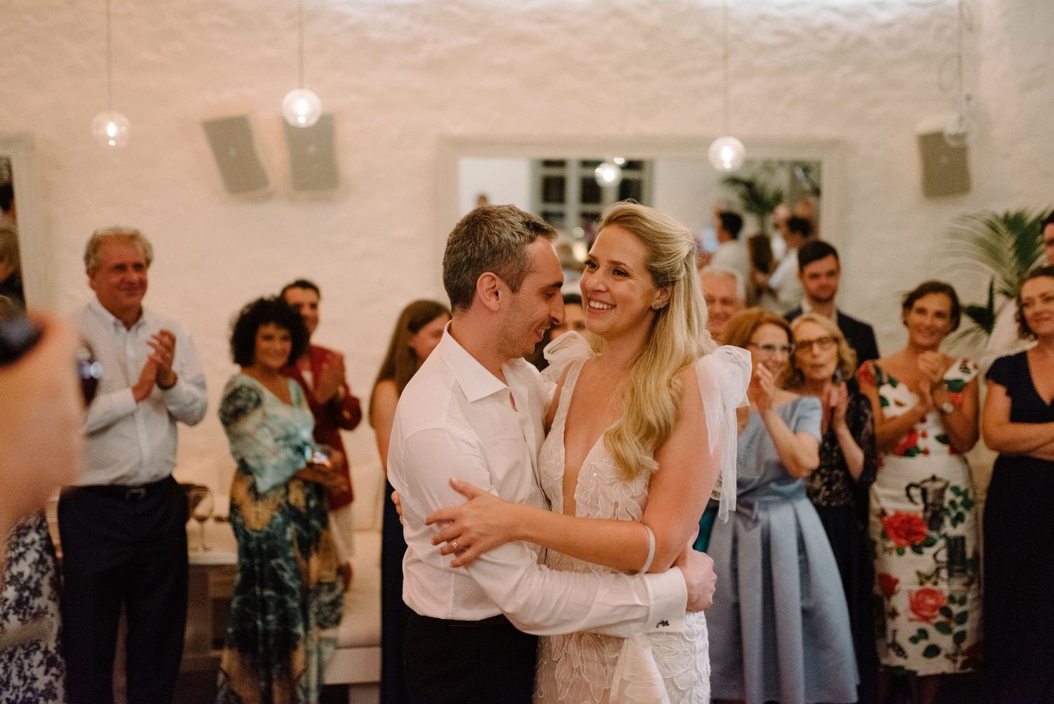 Wedding couple dancing together while guests watch and applaud in a modern venue.