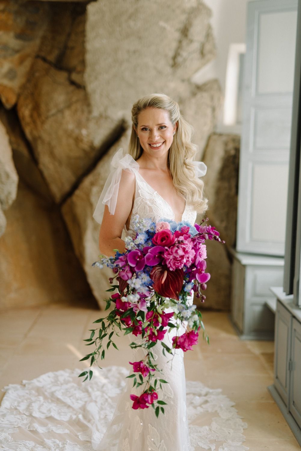 Joyful bridal portrait with dramatic pink and purple cascading bouquet.