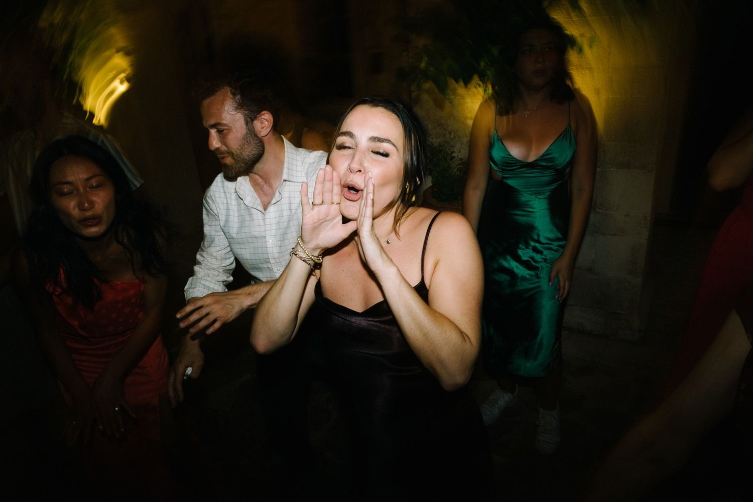Guests dancing and singing passionately at a nighttime celebration.