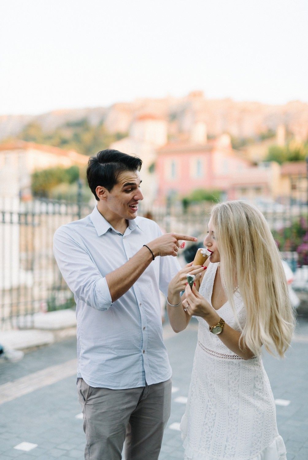 Couple sharing ice cream and laughing together with ancient ruins in the background.