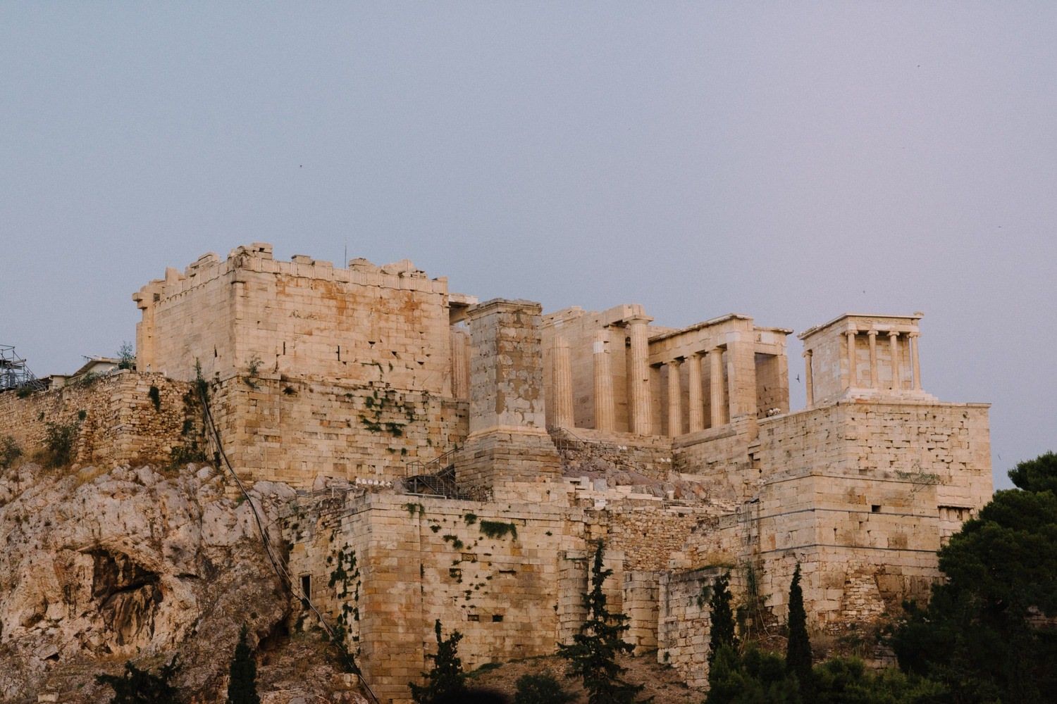 Ancient Acropolis ruins in Athens glowing golden in evening light against blue sky.