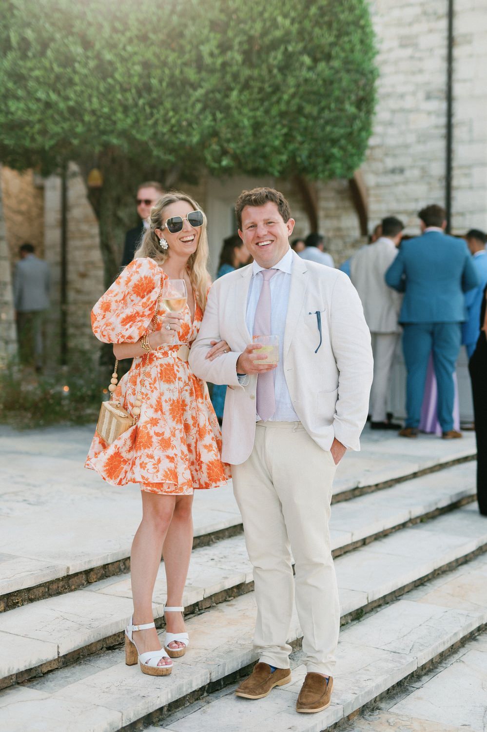 Stylishly dressed guests at a summer party posing on stone steps.