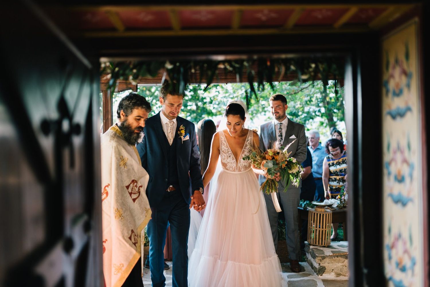 Wedding ceremony procession through a decorated rustic doorway with painted details.