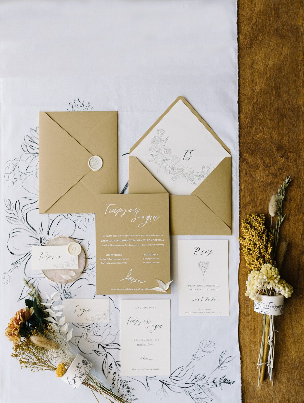 Wedding invitation suite with elegant floral illustrations and kraft paper envelopes laid out on a wooden table.
