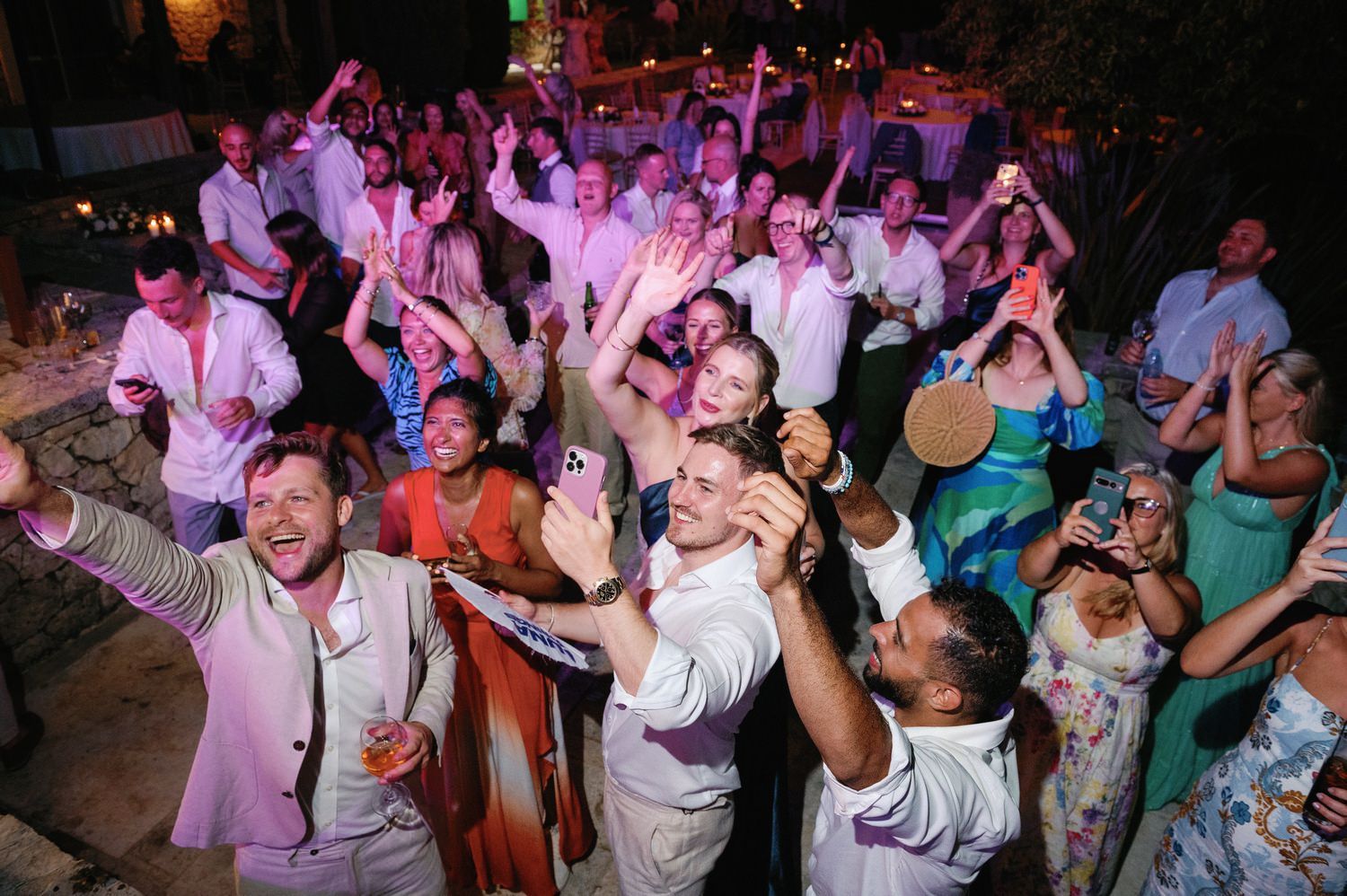 Joyful wedding guests dancing and celebrating together on a packed dance floor.