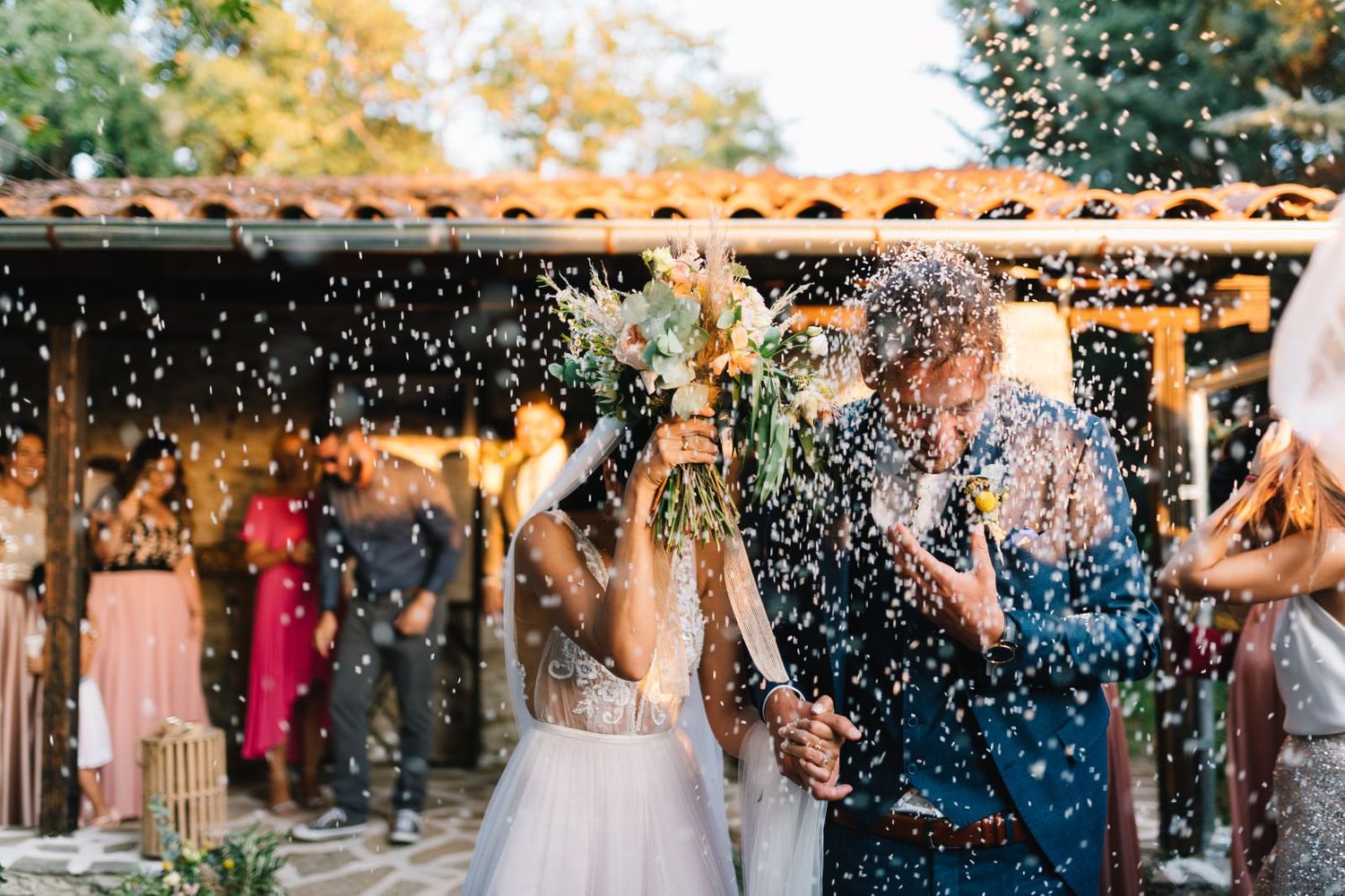 couple leave the church and the guests throws weddingrice