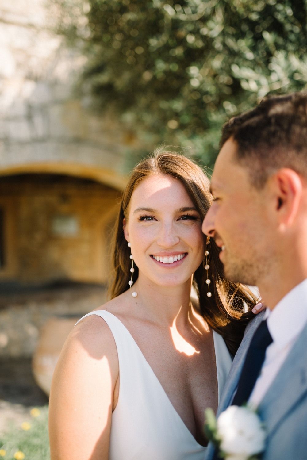 Close-up portrait of a couple in wedding attire sharing a joyful moment outdoors.