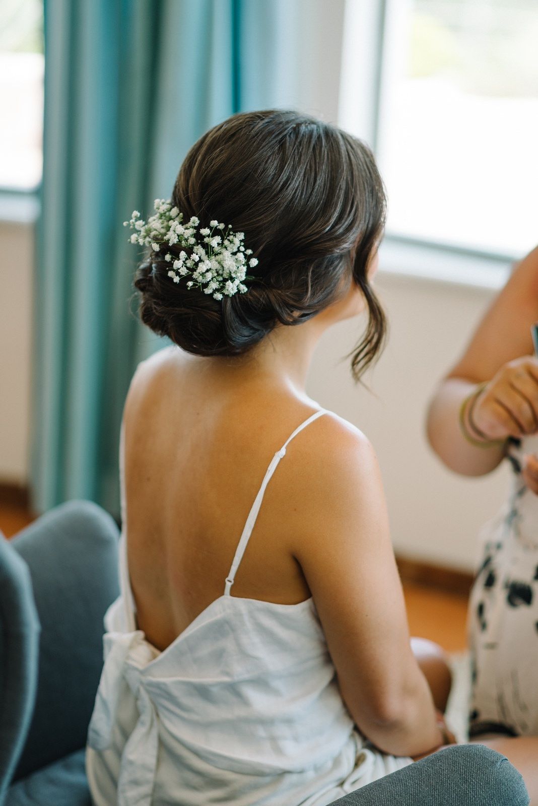 Elegant bridal hairstyle adorned with baby's breath flowers, shot from behind.