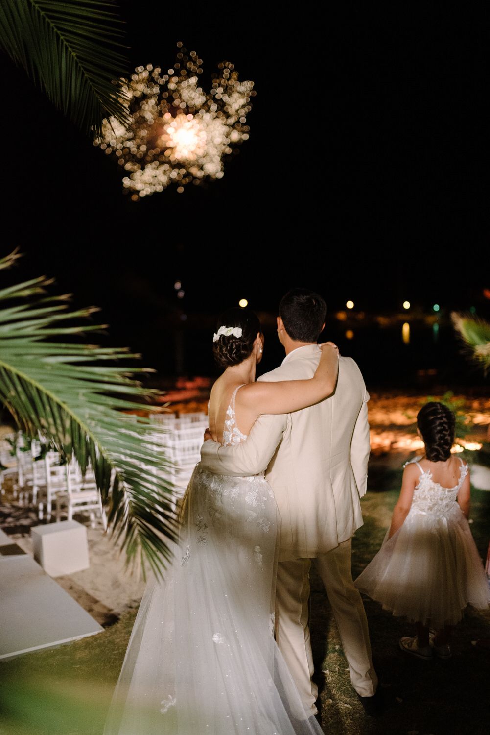 Couple watches fireworks display during romantic nighttime wedding celebration.