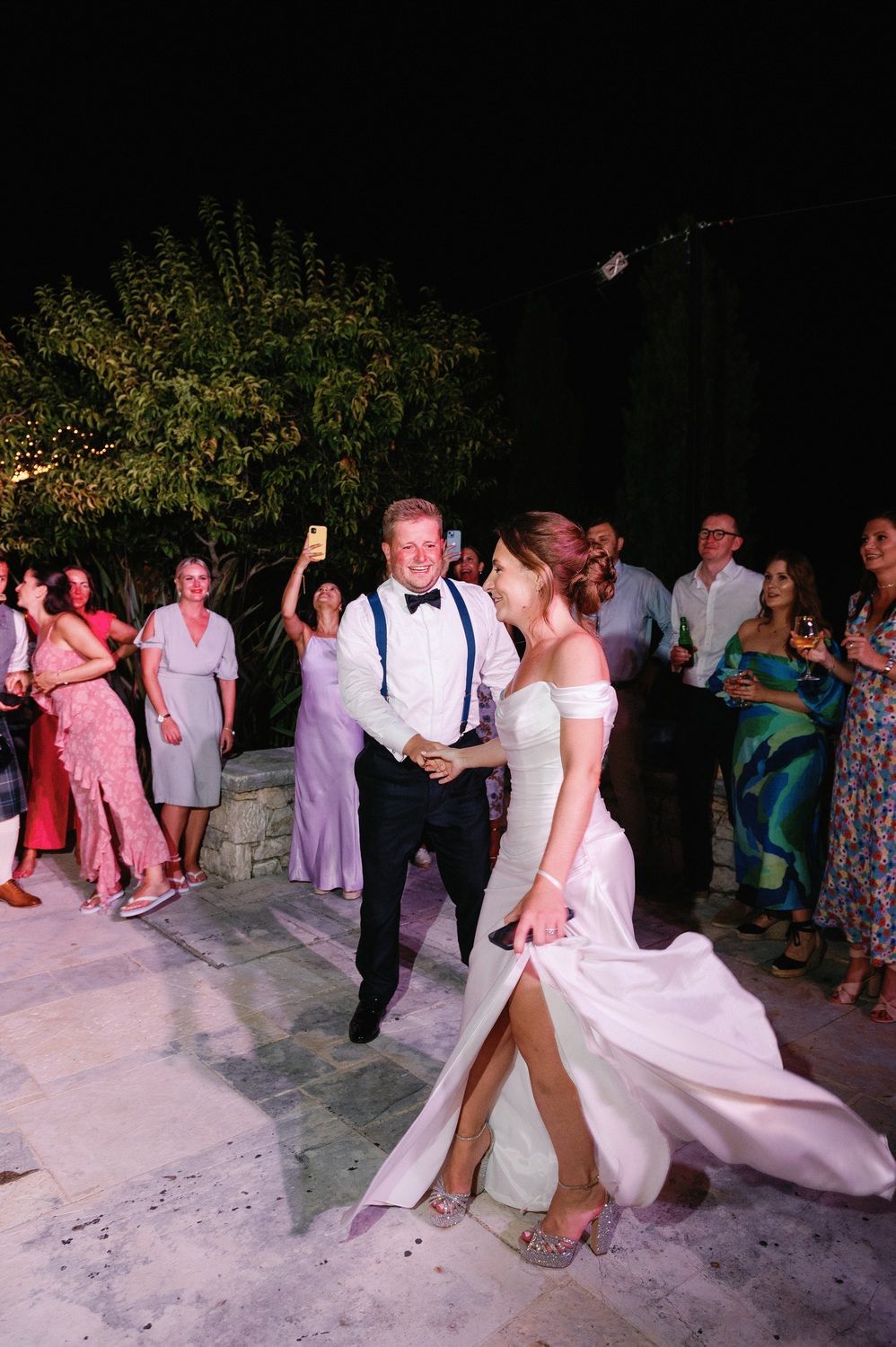 Couple dancing during their first dance at outdoor wedding reception under string lights.