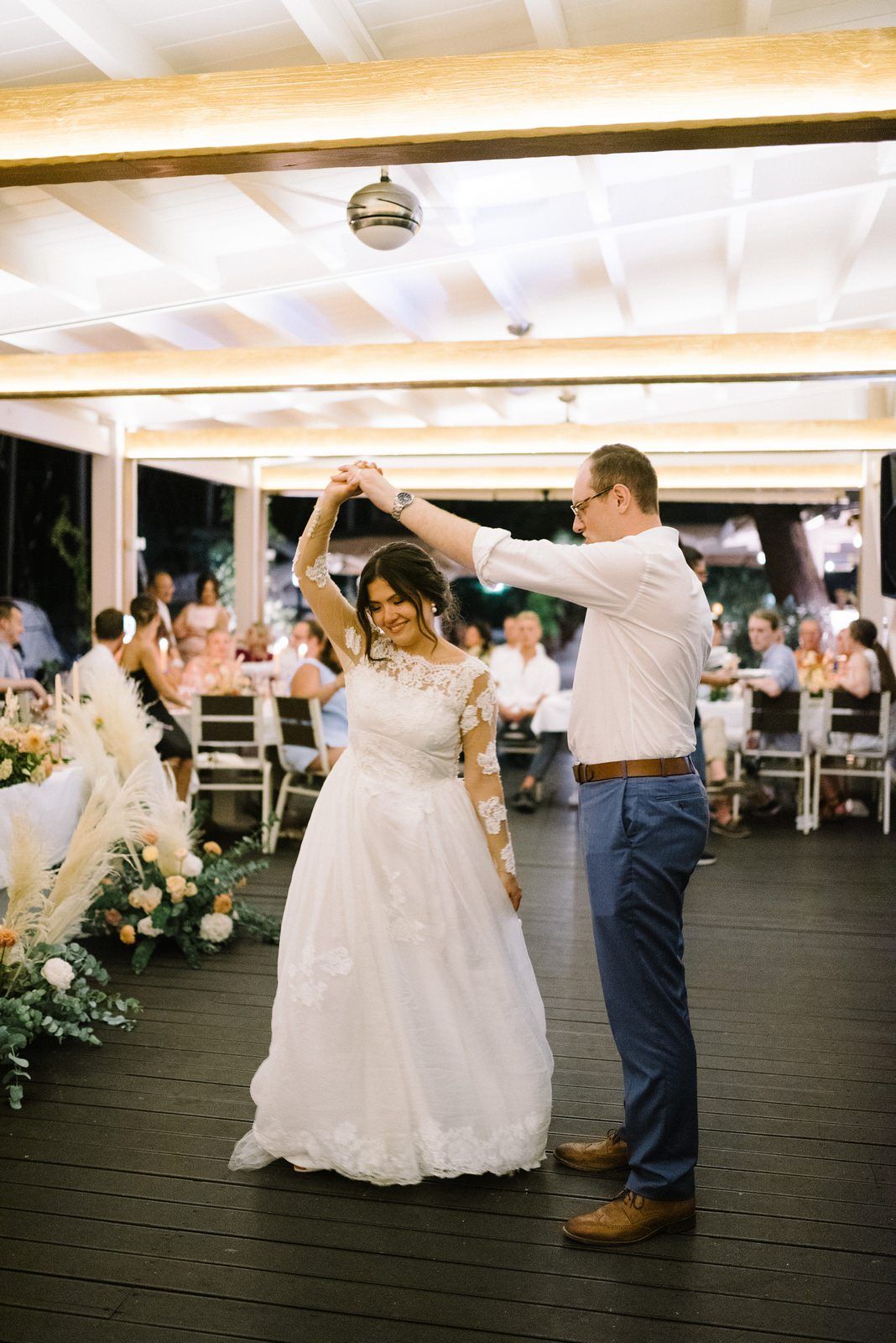 Couple performs their first dance on outdoor deck at wedding reception.