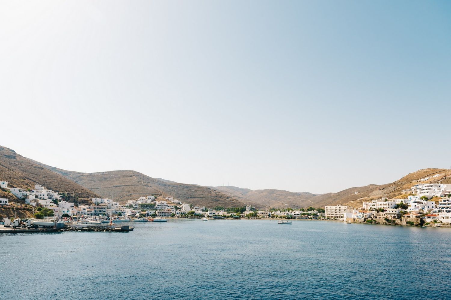 Scenic Mediterranean coastal town with white buildings nestled along a blue harbor bay.