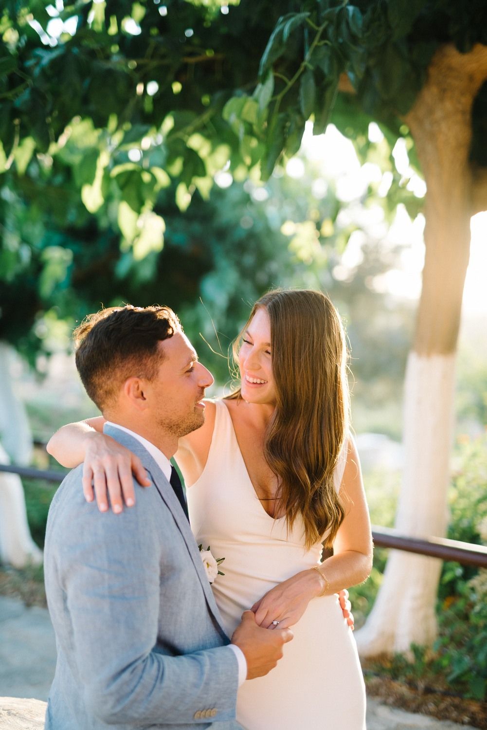 Couple in wedding attire sharing a romantic moment in a sunlit garden setting.
