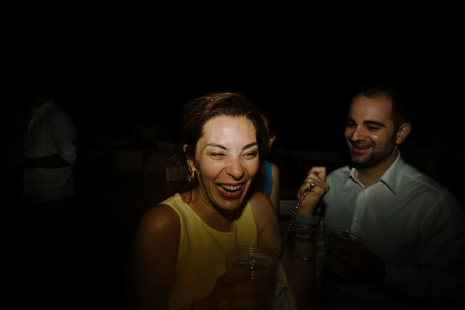 Party guests enjoying themselves in dark ambient lighting at evening celebration.