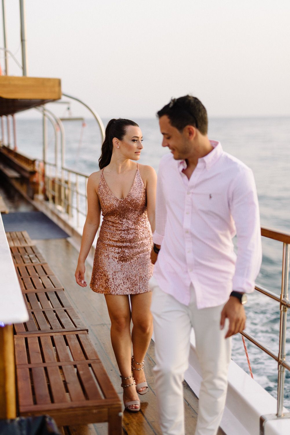 Couple walking together on a wooden ship deck during sunset cruise.