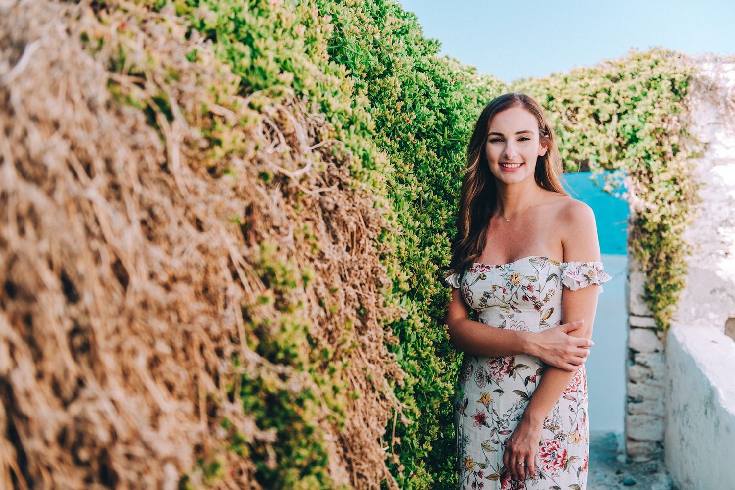 A sunny portrait beside vine-covered walls in a Mediterranean setting.