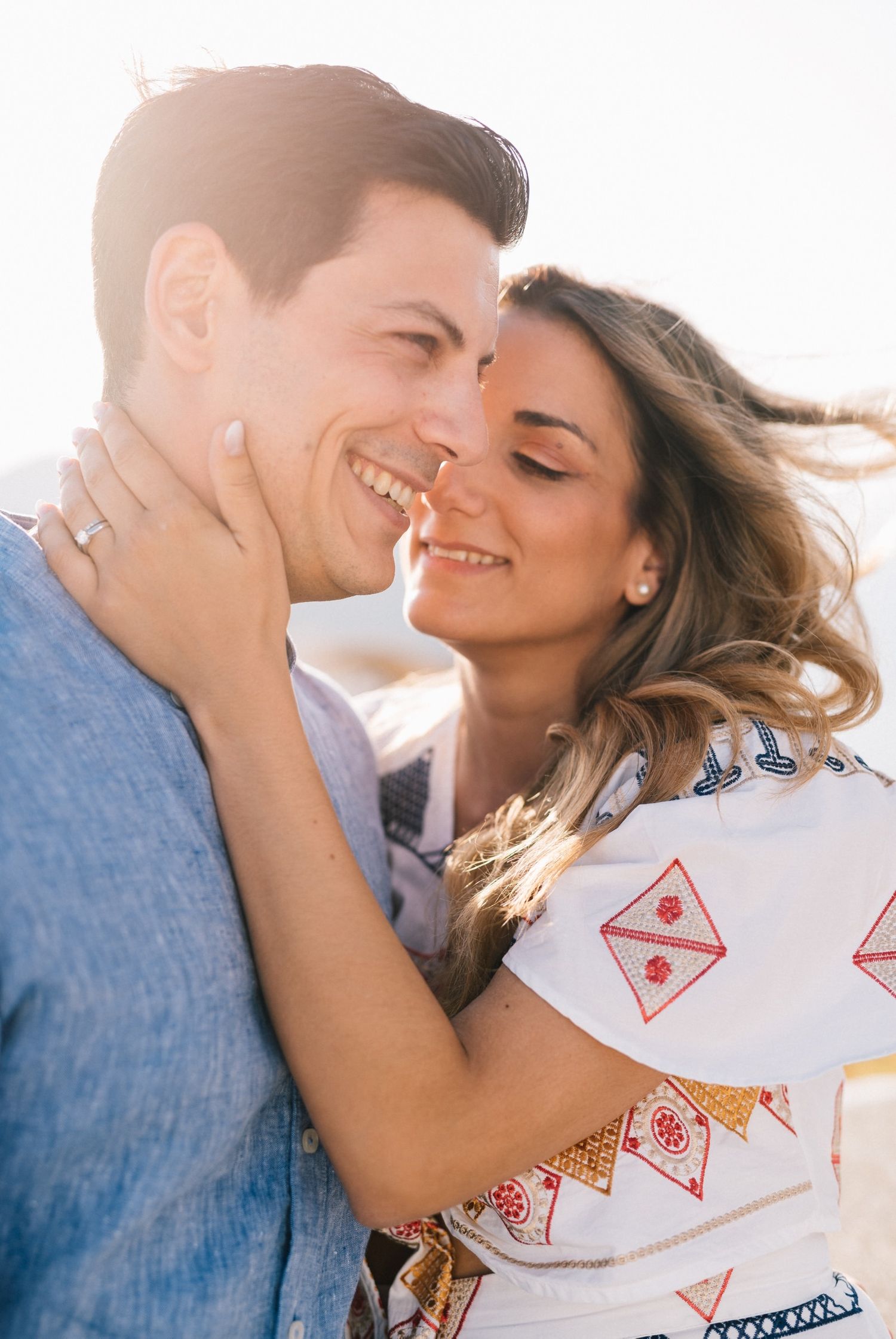 Candid moment of couple laughing and embracing in golden hour light.