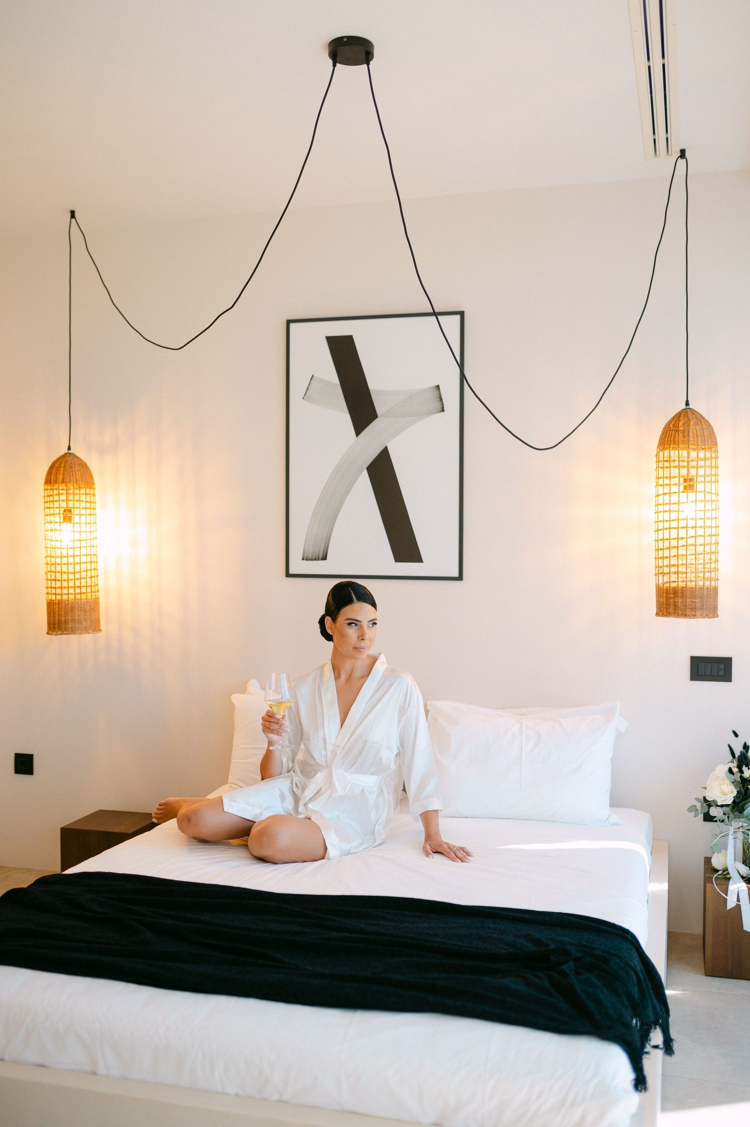 A series of four photos showing a white hotel bed with black throw blanket and woven pendant lights above.