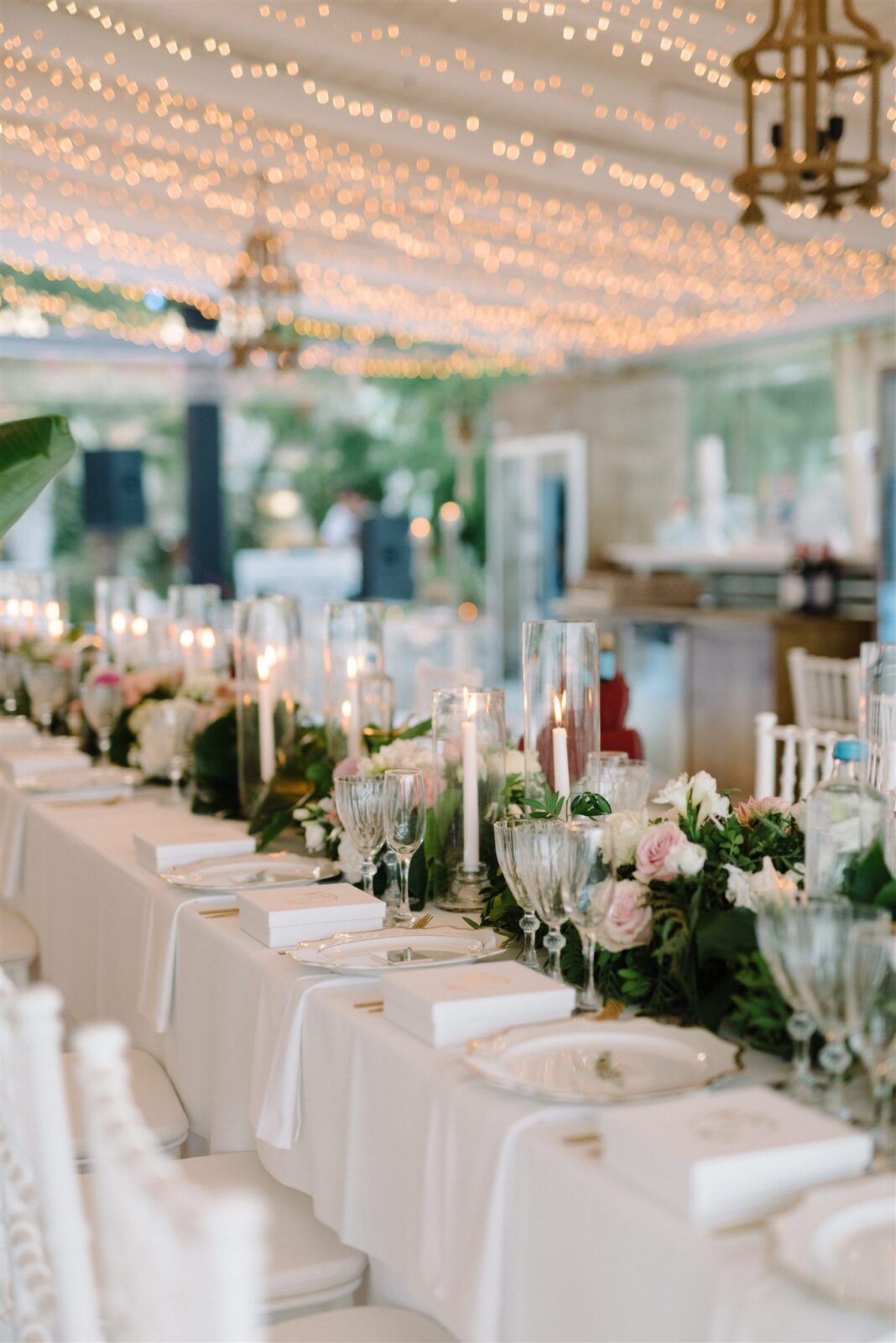 Elegant wedding reception table settings under twinkling string lights with white linens and floral centerpieces at Parga Greece