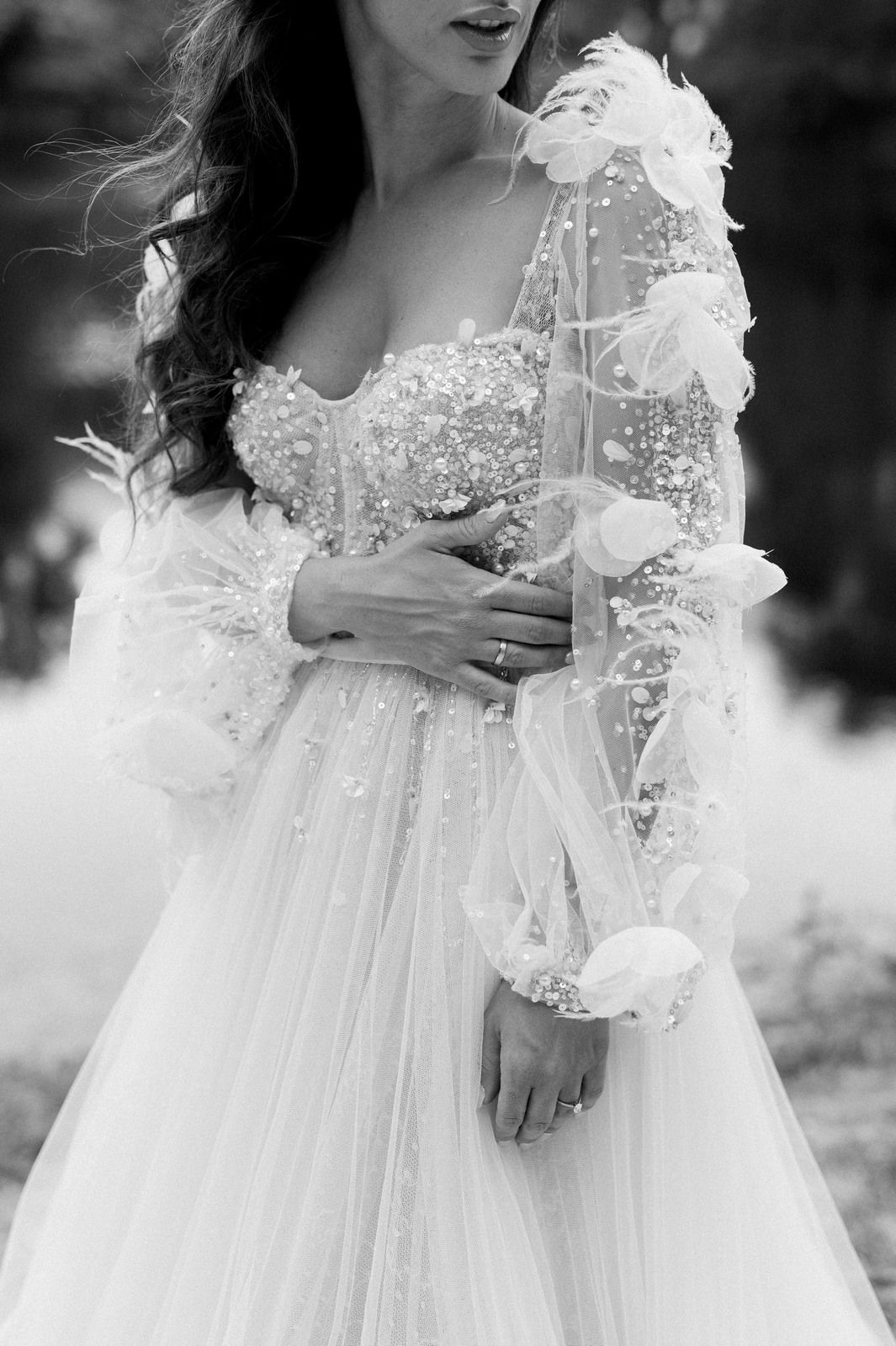 Close-up details of an ethereal white wedding dress with delicate lace and floral embellishments in black and white.