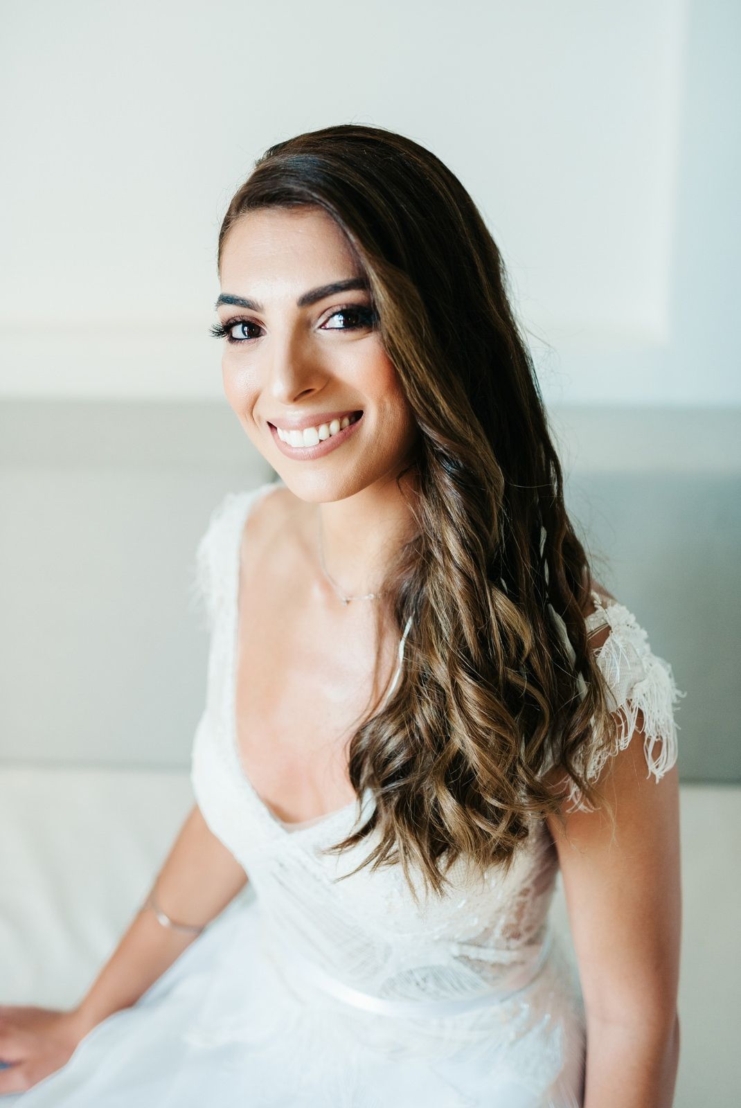 Beautiful bridal portrait featuring wavy brown hair and lace wedding dress.