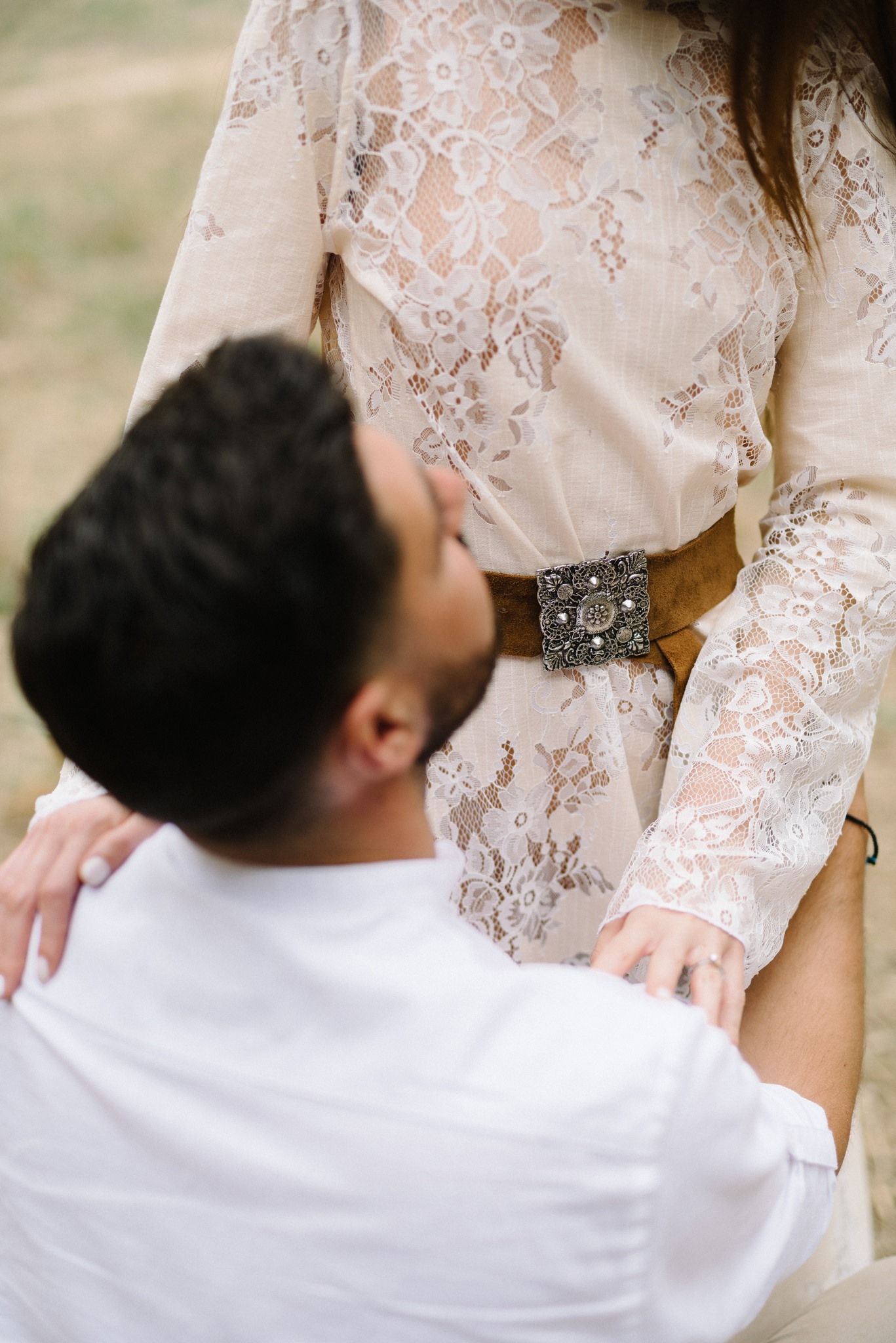 Close-up of couple embracing, showing detailed lace dress and white shirt.