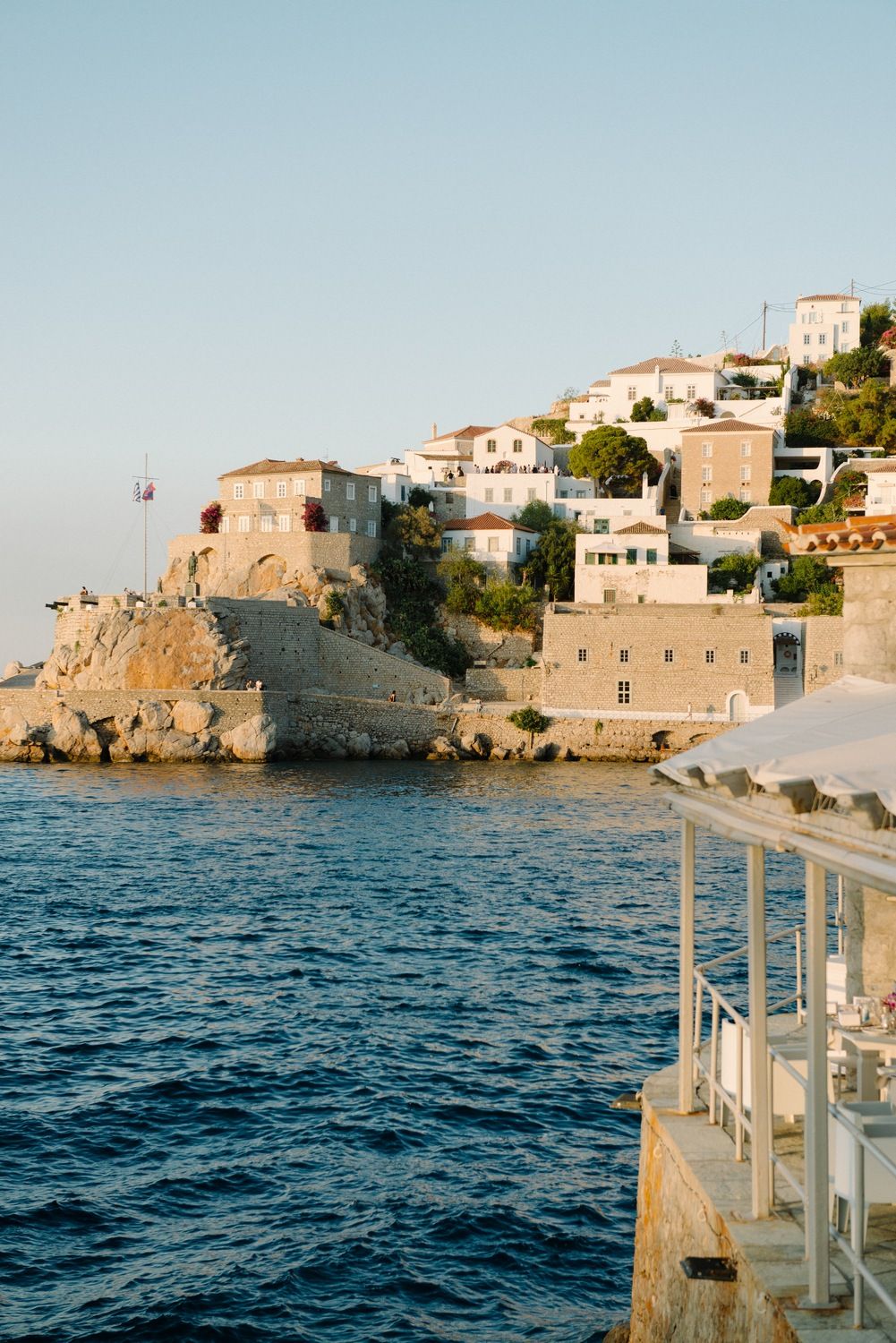 Mediterranean coastal village with traditional stone buildings perched on cliffs above blue waters.