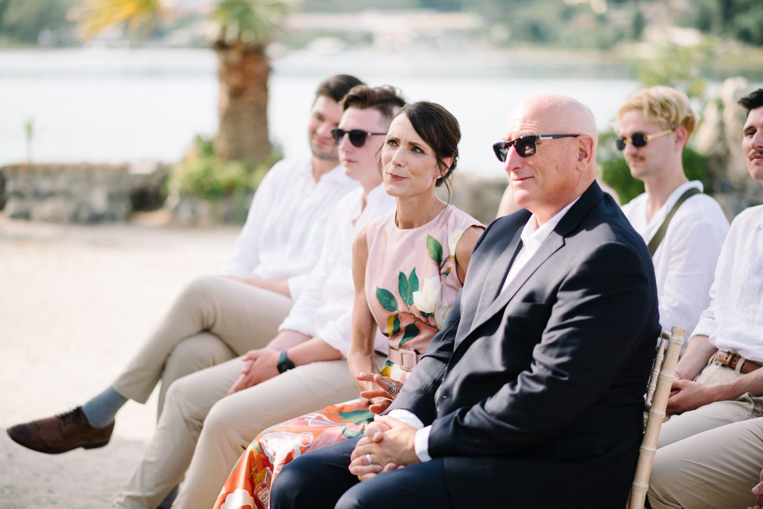 Wedding guests seated outdoors enjoying the ceremony in a coastal setting.