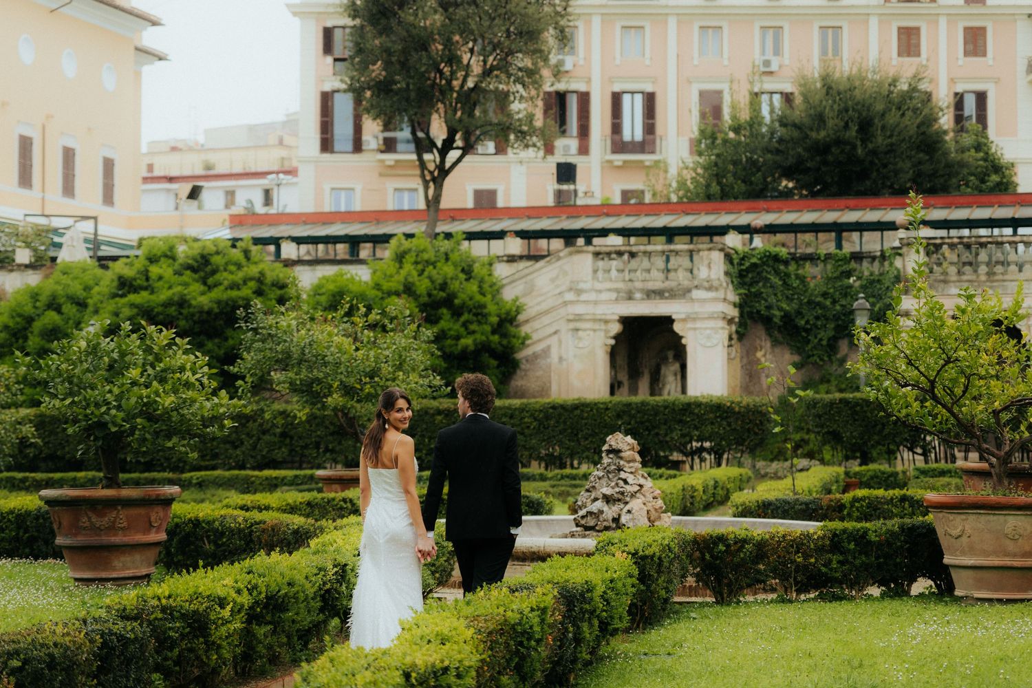 Intimate manor wedding portrait with couple walking through historic estate grounds
