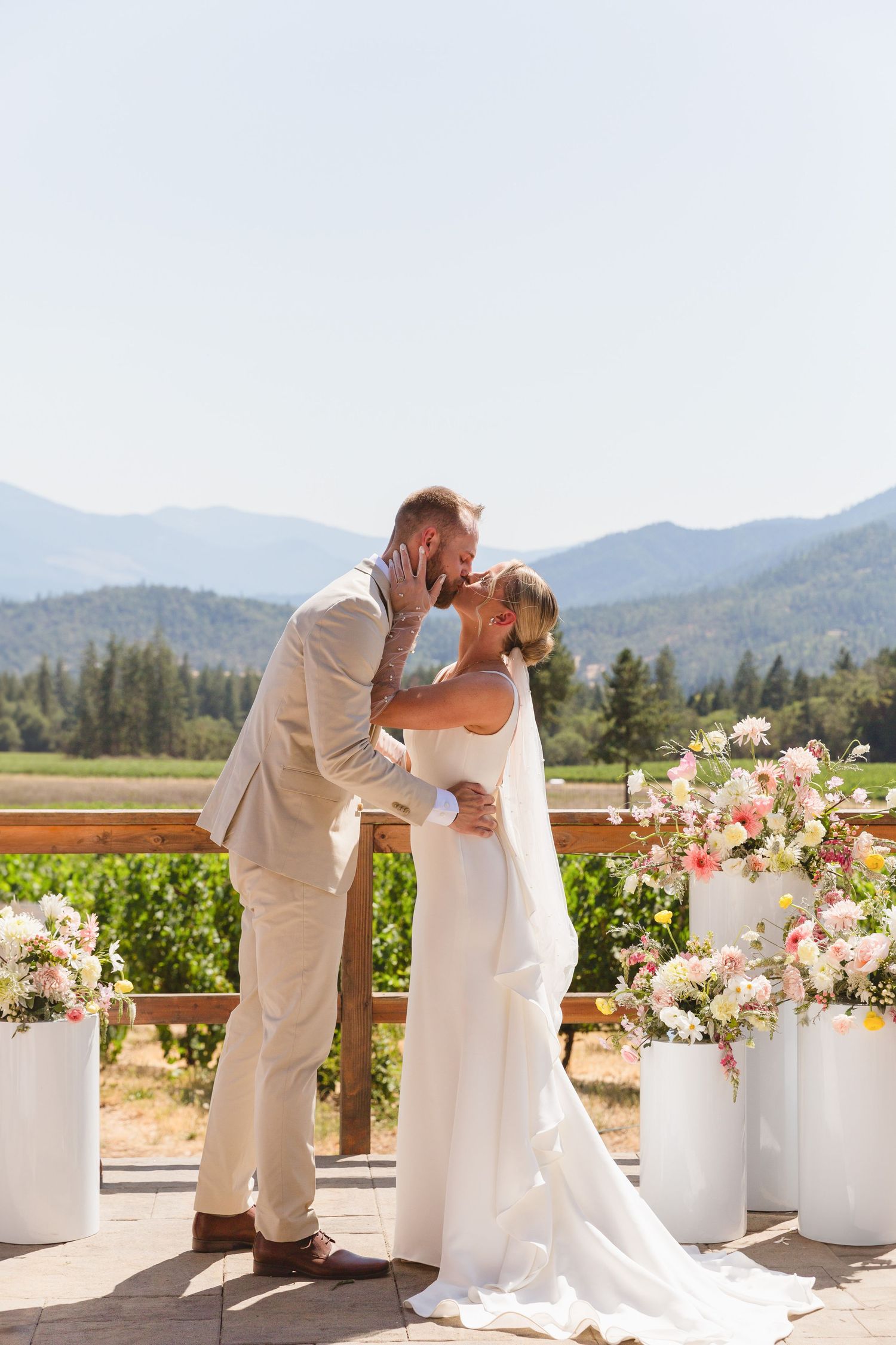 A mountain wedding ceremony with white floral arrangements and mountains in the background.