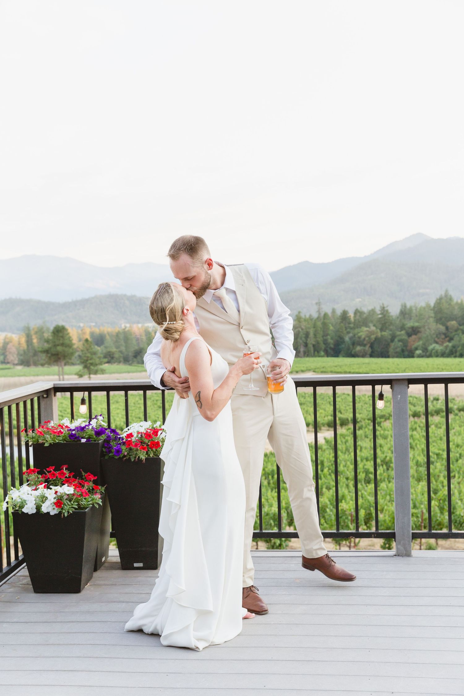 A couple shares a romantic dance moment on an outdoor deck with mountain views and colorful flower planters.