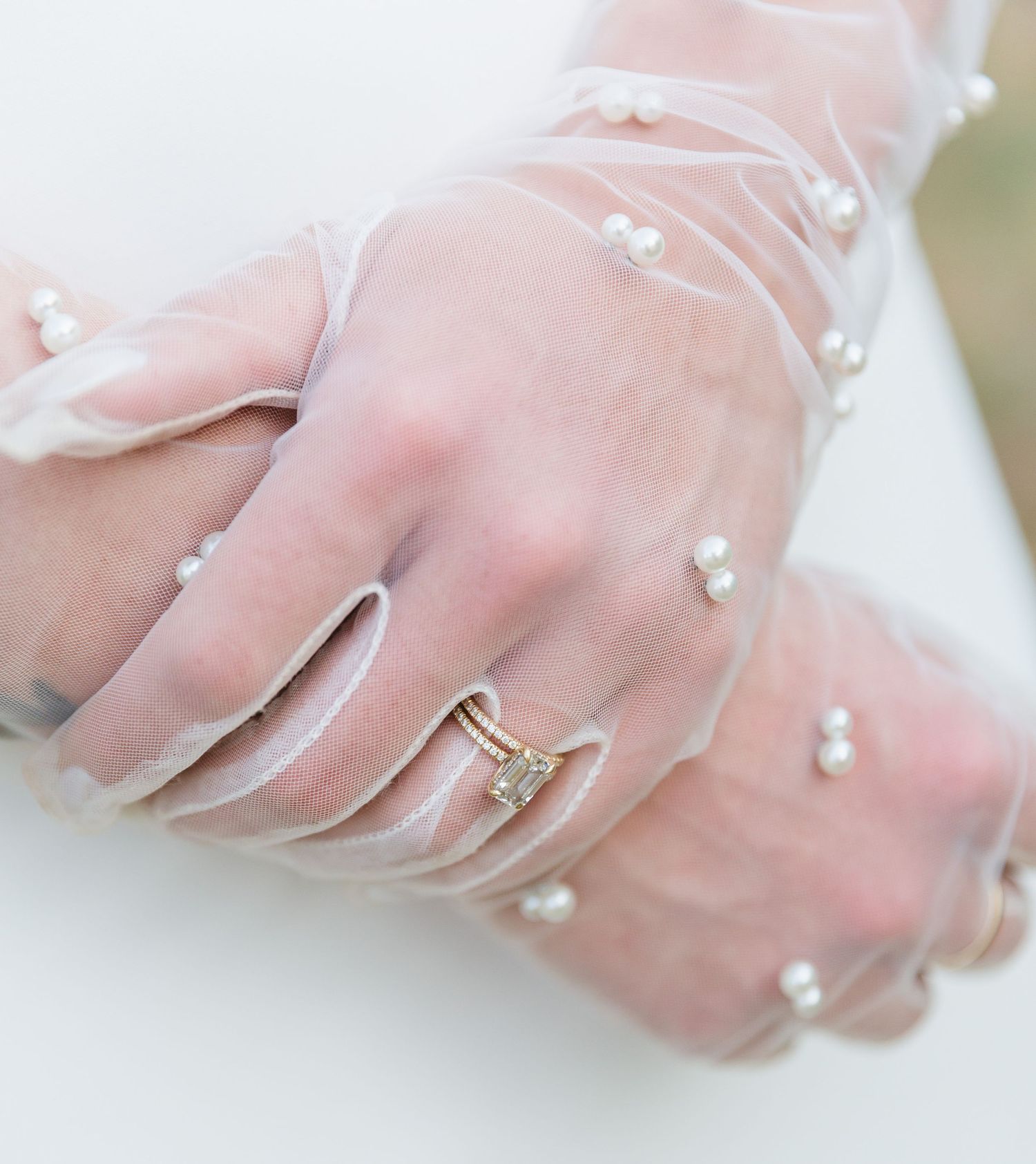 Close-up detail shots of delicate sheer fabric with pearl embellishments and a wedding ring.