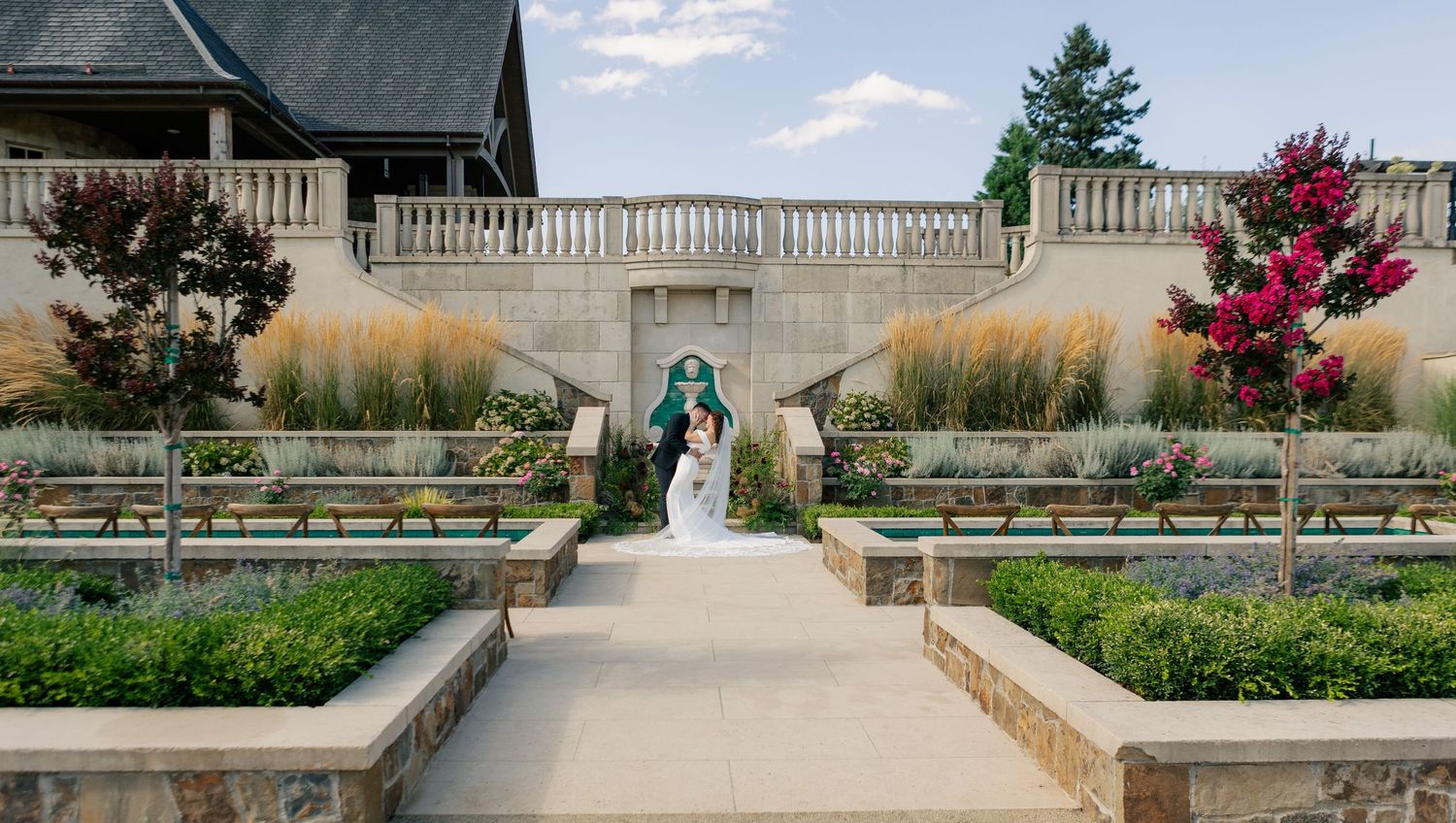Elegant stone patio and terrace with formal garden landscaping at a luxury estate venue.