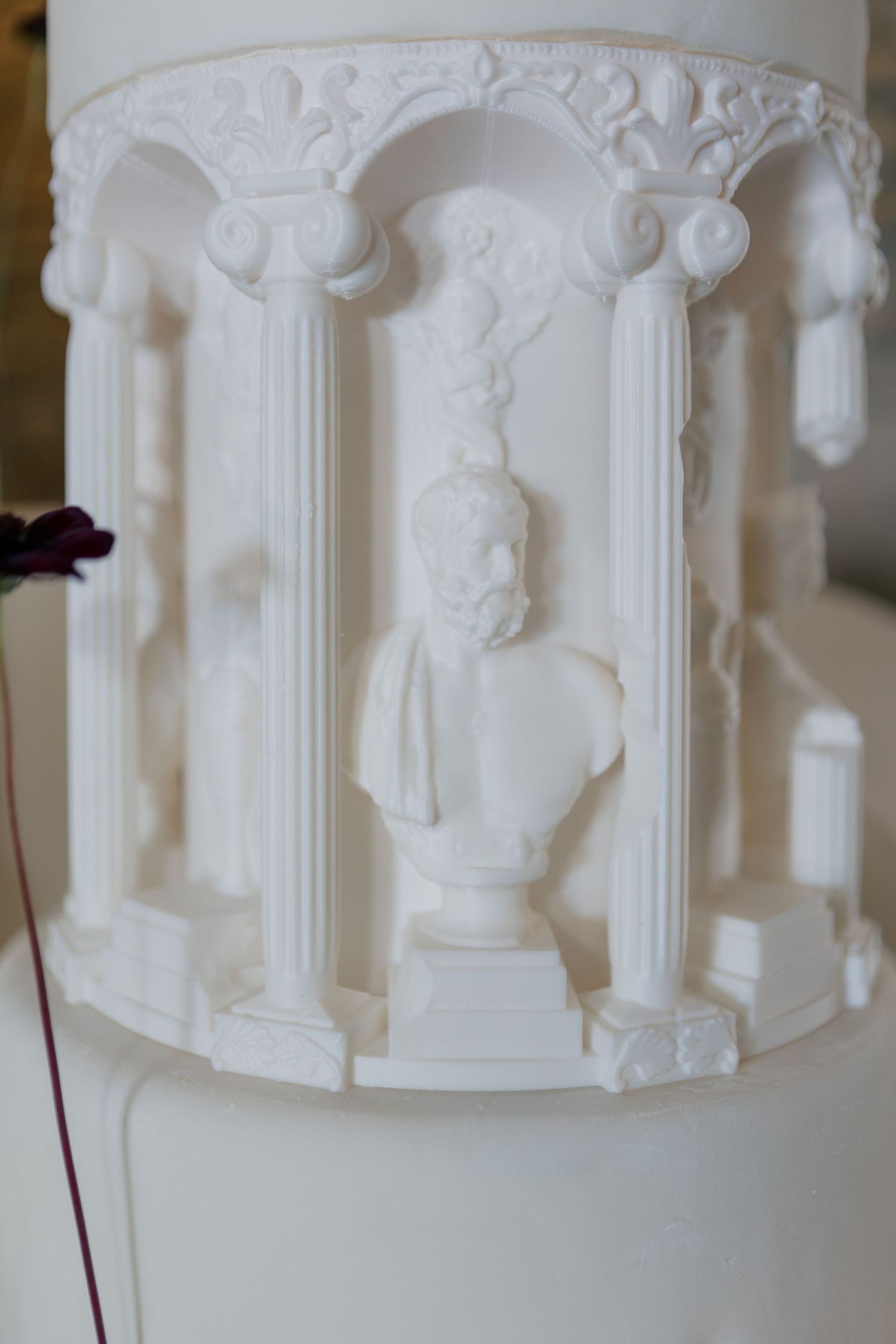 White decorative wedding cake with classical architectural relief details featuring columns and ornate moldings.